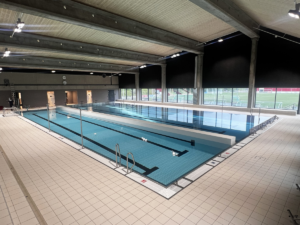 Movable floor with hinged wall in a public pool